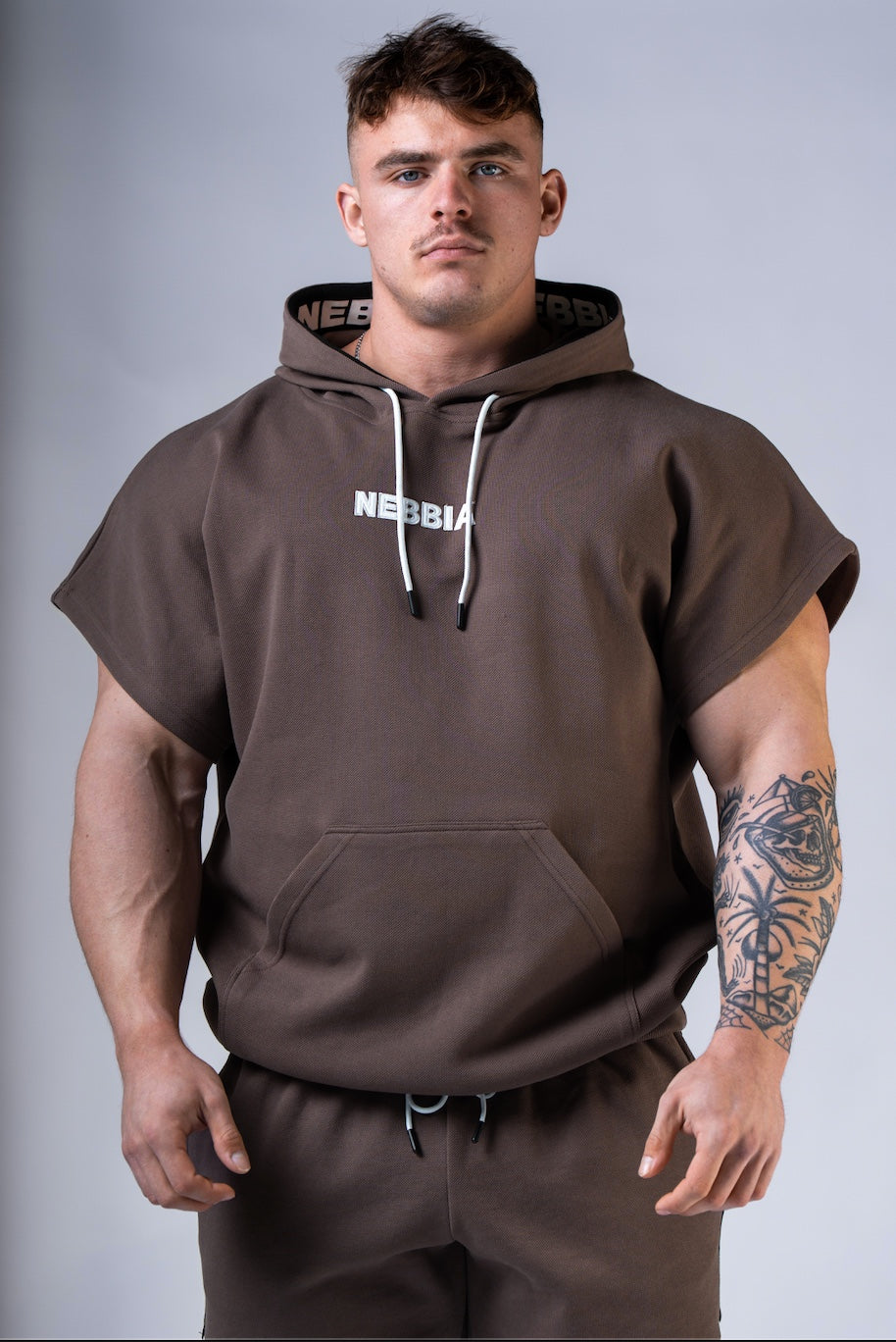 Front view of NEBBIA Hero 297 Training Rag Top in Black/Brown, highlighting the athletic cut and chest logo.